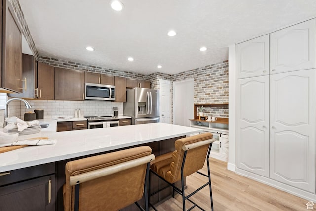 2104 W Champagne Cir, Taylorsville, UT 84129 - kitchen with appliances with stainless steel finishes, light wood-type flooring, tasteful backsplash, recessed lighting, and a peninsula
