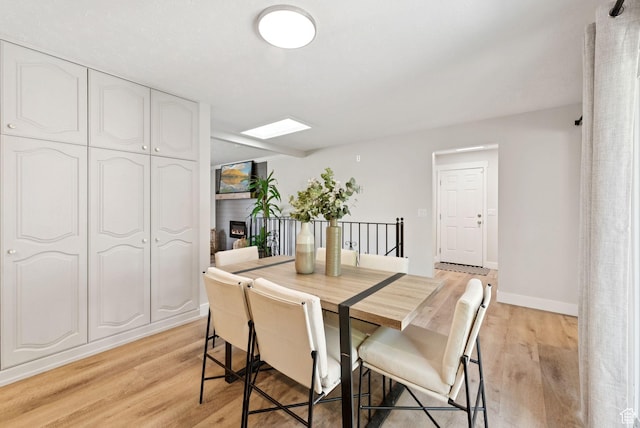 2104 W Champagne Cir, Taylorsville, UT 84129 - dining area with light wood-type flooring and a lit fireplace