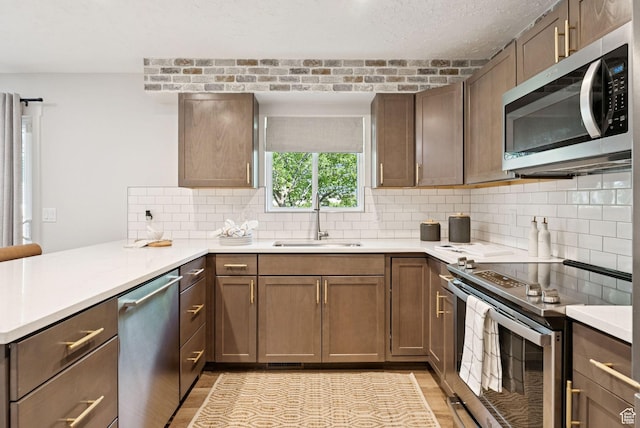 2104 W Champagne Cir, Taylorsville, UT 84129 - kitchen featuring stainless steel appliances, a peninsula, backsplash, light countertops, and light wood-style floors