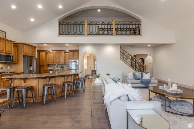 10677 S Amberley Ln E, Sandy, UT 84094 - living area featuring high vaulted ceiling, arched walkways, wood finished floors, recessed lighting, and stairs