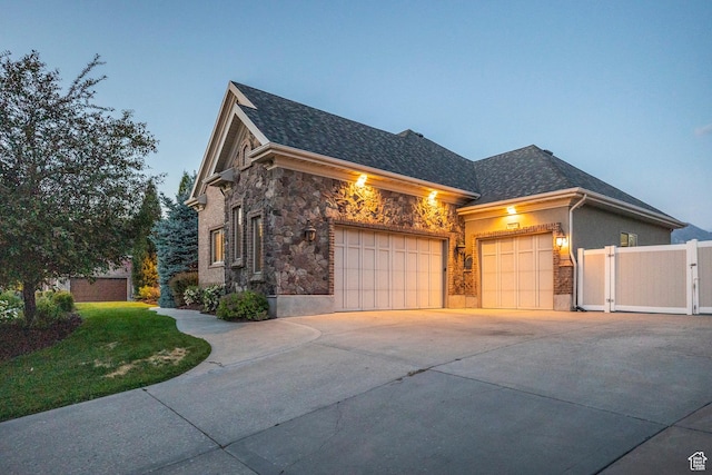 10677 S Amberley Ln E, Sandy, UT 84094 - view of side of property with stone siding, an attached garage, driveway, and roof with shingles