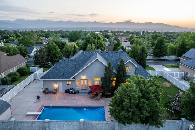 10677 S Amberley Ln E, Sandy, UT 84094 - pool at dusk featuring a mountain view, a fenced backyard, entry steps, and a patio area