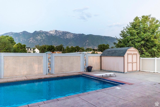 10677 S Amberley Ln E, Sandy, UT 84094 - view of swimming pool featuring a shed, a patio area, a mountain view, and a diving board
