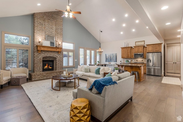 10677 S Amberley Ln E, Sandy, UT 84094 - living room with high vaulted ceiling, a ceiling fan, light wood-style floors, a brick fireplace, and healthy amount of natural light