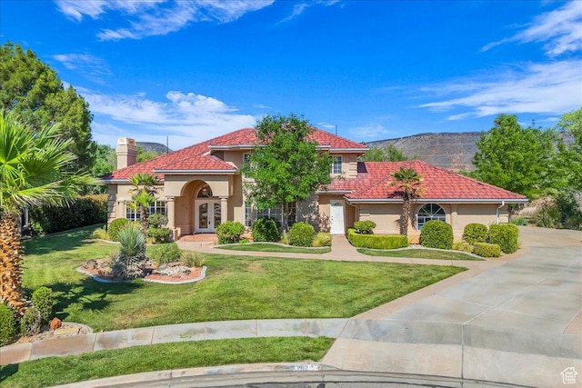1912 W Rivers Edge Ln, St George, UT 84770 - mediterranean / spanish-style home featuring stucco siding, french doors, a chimney, a front lawn, and a tile roof
