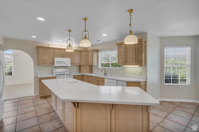 1912 W Rivers Edge Ln, St George, UT 84770 - kitchen featuring white appliances, an island with sink, light countertops, light brown cabinets, and a textured ceiling