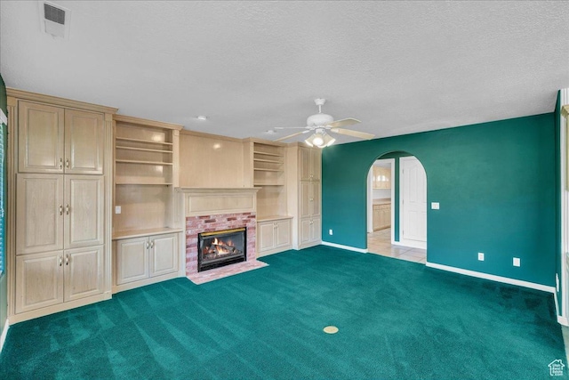 1912 W Rivers Edge Ln, St George, UT 84770 - unfurnished living room featuring arched walkways, a ceiling fan, carpet, a textured ceiling, and a fireplace