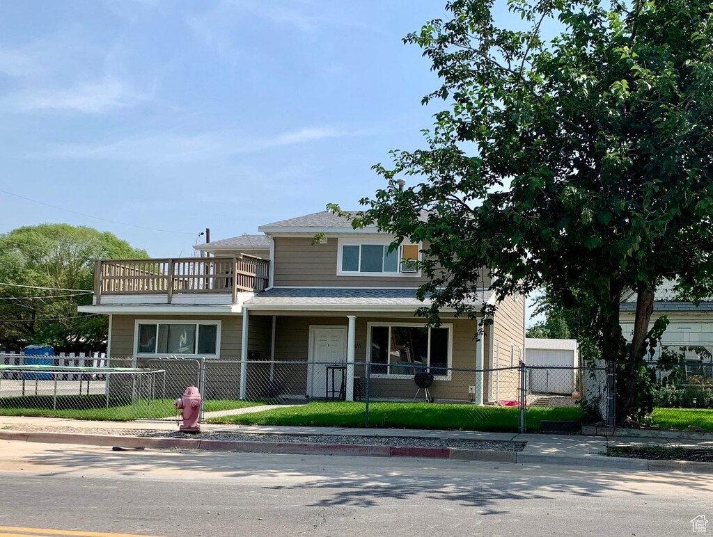 7805 S Main St, Midvale, UT 84047 - view of front of house with a balcony, a fenced front yard, and a porch