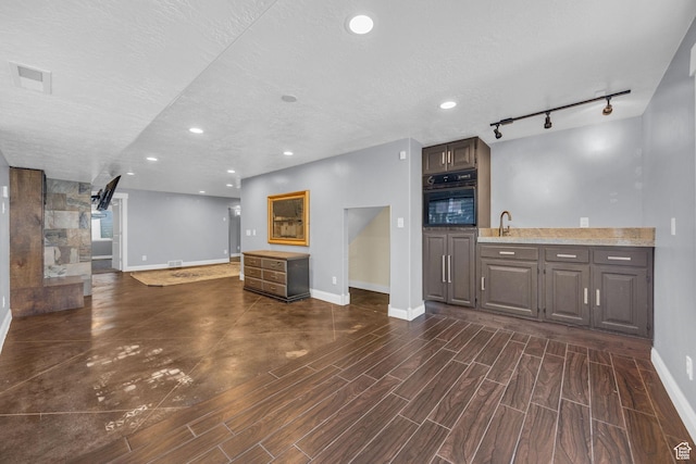 2352 N 1160 W, Clinton, UT 84015 - unfurnished living room featuring dark wood-style floors, rail lighting, recessed lighting, and a textured ceiling
