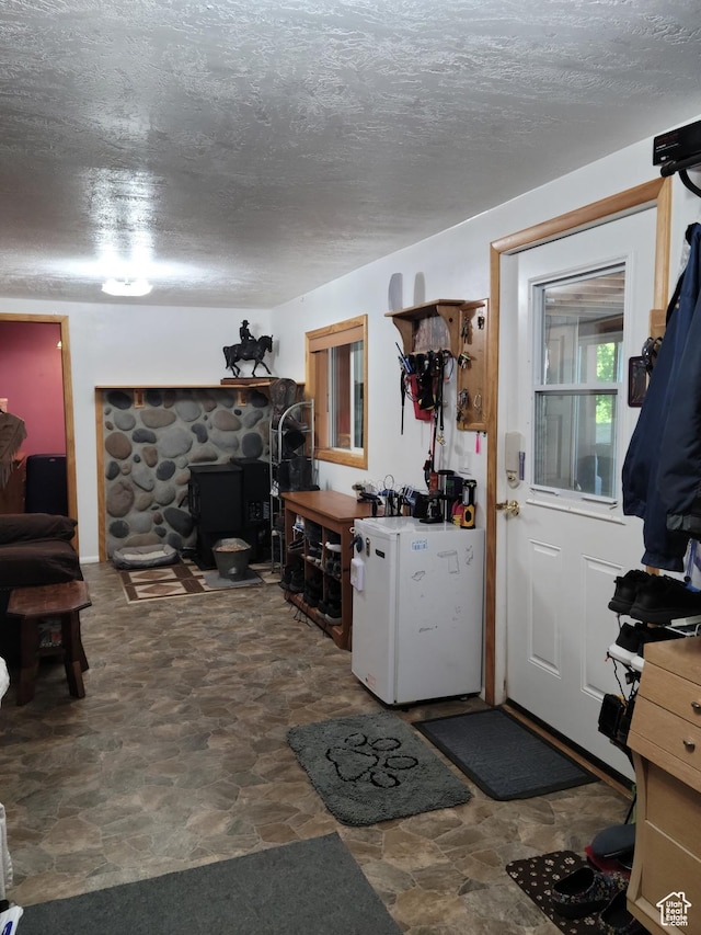 97 Main St, Ophir, UT 84071 - kitchen featuring stone finish flooring, a wood stove, a textured ceiling, and refrigerator
