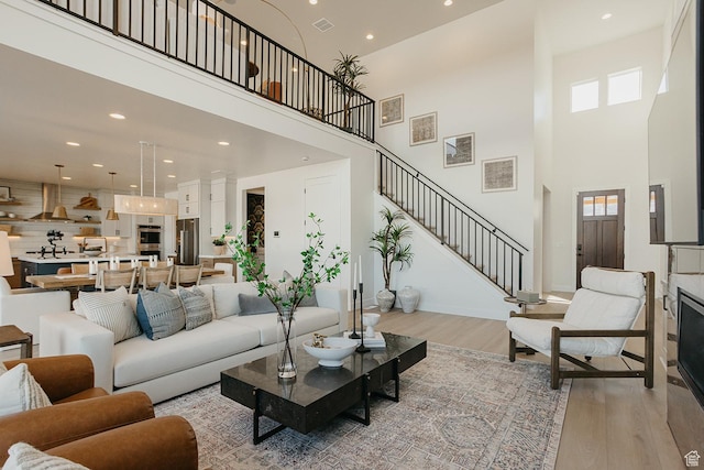 3488 E 1120 S Unit 115, Spanish Fork, UT 84660 - living room featuring light wood finished floors, a towering ceiling, stairway, plenty of natural light, and recessed lighting