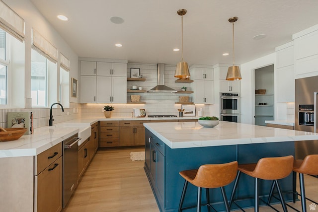 3488 E 1120 S Unit 115, Spanish Fork, UT 84660 - kitchen featuring open shelves, appliances with stainless steel finishes, wall chimney exhaust hood, a kitchen bar, and a kitchen island