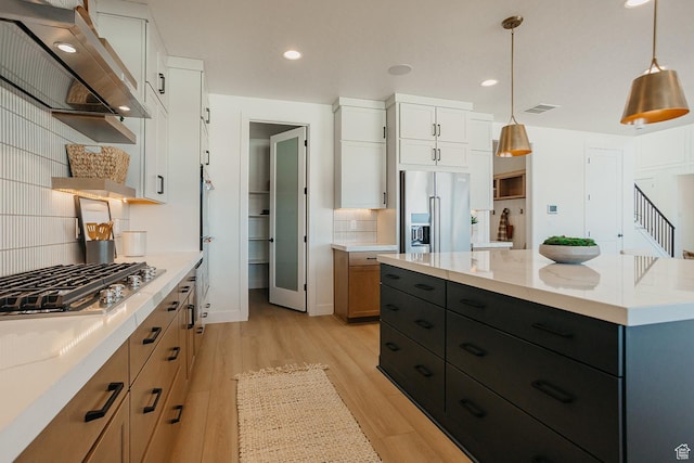 3488 E 1120 S Unit 115, Spanish Fork, UT 84660 - kitchen featuring stainless steel appliances, wall chimney range hood, decorative backsplash, light wood finished floors, and white cabinets