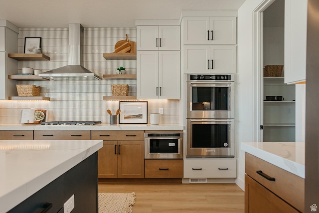 3488 E 1120 S Unit 115, Spanish Fork, UT 84660 - kitchen featuring open shelves, stainless steel appliances, wall chimney exhaust hood, light wood-style flooring, and decorative backsplash
