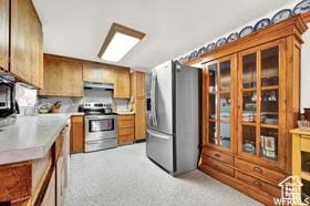 1708 Hislop Dr, Ogden, UT 84404 - kitchen featuring appliances with stainless steel finishes, extractor fan, light countertops, brown cabinetry, and glass insert cabinets