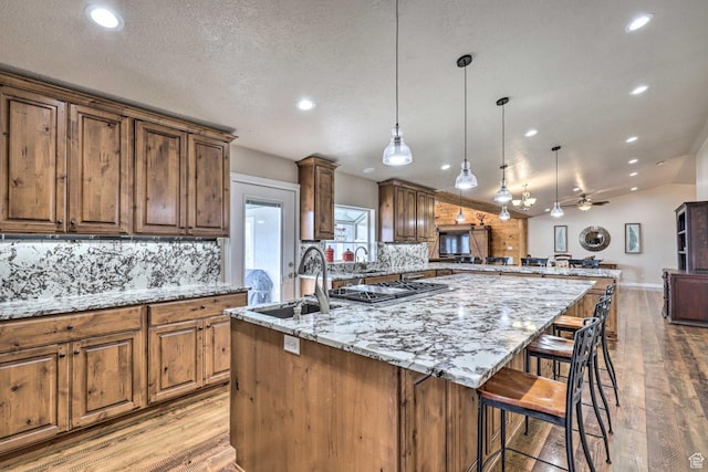3572 Wild Mare Way, Heber City, UT 84032 - kitchen featuring an island with sink, recessed lighting, backsplash, stainless steel gas stovetop, and light stone counters
