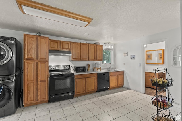 165 N 800 E, Hyrum, UT 84319 - kitchen with black appliances, under cabinet range hood, stacked washer / drying machine, brown cabinetry, and light countertops