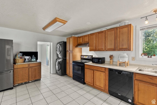 165 N 800 E, Hyrum, UT 84319 - kitchen featuring black appliances, stacked washing machine and dryer, under cabinet range hood, brown cabinets, and a textured ceiling
