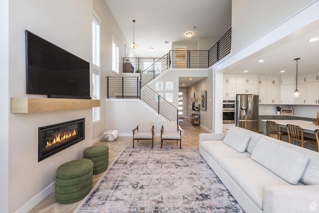 1476 W Stone Gate Dr, Saratoga Springs, UT 84045 - living area with stairway, a glass covered fireplace, recessed lighting, and a high ceiling