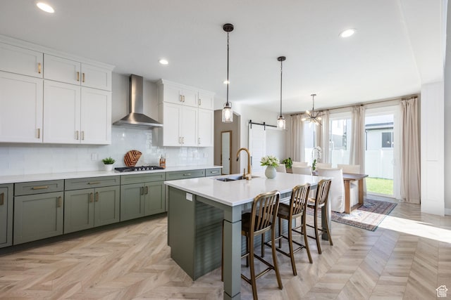 1476 W Stone Gate Dr, Saratoga Springs, UT 84045 - kitchen featuring wall chimney range hood, a barn door, a breakfast bar area, light countertops, and backsplash
