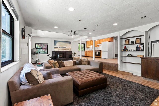 4560 S Wallace Ln, Holladay, UT 84117 - living room with wood finished floors, a wall unit AC, a brick fireplace, and recessed lighting