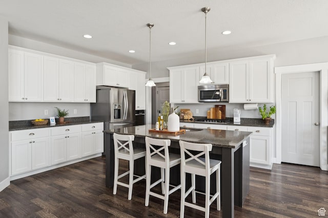 13698 S Black Hoof Cir, Herriman, UT 84096 - kitchen with appliances with stainless steel finishes, recessed lighting, a kitchen island with sink, dark wood finished floors, and white cabinets