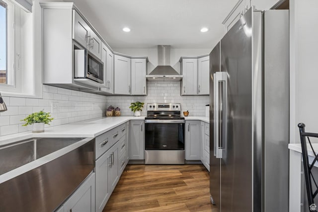 34 Valley View Dr, Springdale, UT 84767 - kitchen with appliances with stainless steel finishes, wall chimney exhaust hood, gray cabinetry, tasteful backsplash, and dark wood finished floors