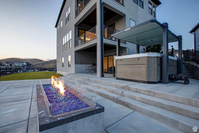 4473 N Solstice Dr, Lehi, UT 84043 - patio terrace at dusk with a fire pit, a hot tub, a patio, a balcony, and a mountain view