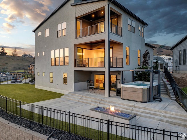 4473 N Solstice Dr, Lehi, UT 84043 - back of house at dusk with a balcony, a hot tub, a patio area, a fire pit, and stucco siding