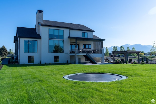 1889 W 1400 S, Lehi, UT 84043 - rear view of house featuring a trampoline, a lawn, stucco siding, a mountain view, and a chimney