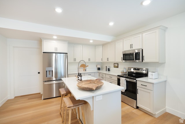 1889 W 1400 S, Lehi, UT 84043 - kitchen with stainless steel appliances, a kitchen island with sink, light wood-style flooring, a kitchen breakfast bar, and light countertops