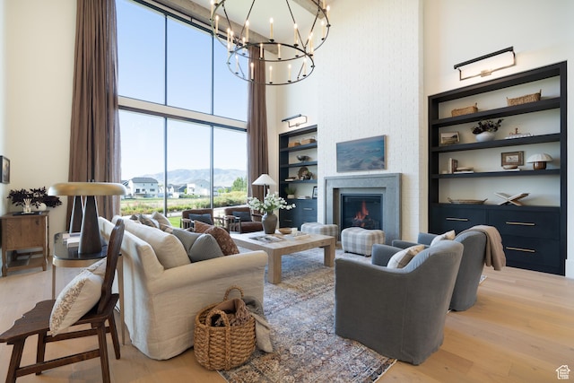 1889 W 1400 S, Lehi, UT 84043 - living room with a high ceiling, light wood-style flooring, a chandelier, a lit fireplace, and a mountain view