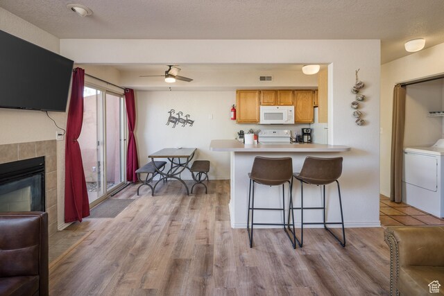 3287 E Fairway Loop, Moab, UT 84532 - kitchen featuring white appliances, washer / dryer, a kitchen breakfast bar, light countertops, and light wood-style flooring