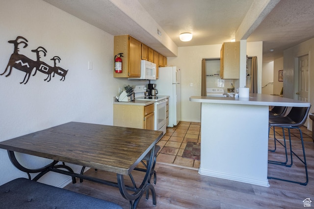 3287 E Fairway Loop, Moab, UT 84532 - kitchen featuring white appliances, a breakfast bar area, light countertops, a peninsula, and wood finished floors