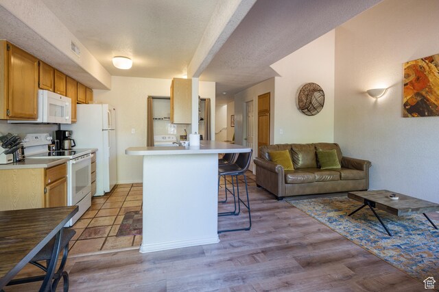 3287 E Fairway Loop, Moab, UT 84532 - kitchen with white appliances, a breakfast bar, open floor plan, light countertops, and a textured ceiling