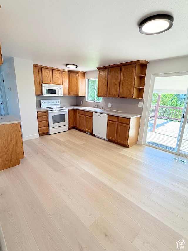 3841 W Bluebird Cir, West Valley City, UT 84120 - kitchen with white appliances, light wood-type flooring, brown cabinetry, and light countertops