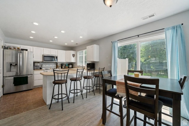 1021 Sara Ln, Ogden, UT 84404 - kitchen with stainless steel appliances, white cabinetry, recessed lighting, a peninsula, and a kitchen bar