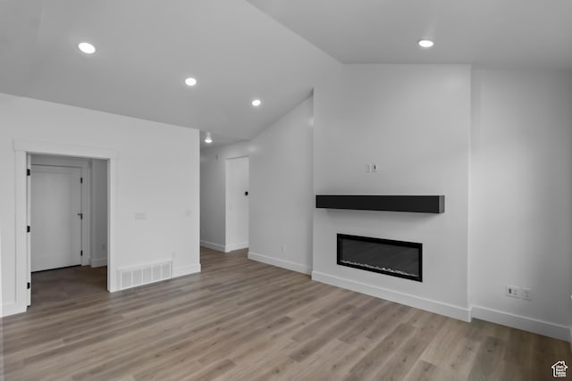 233 E 580 N, Providence, UT 84332 - unfurnished living room featuring a glass covered fireplace, light wood finished floors, lofted ceiling, and recessed lighting