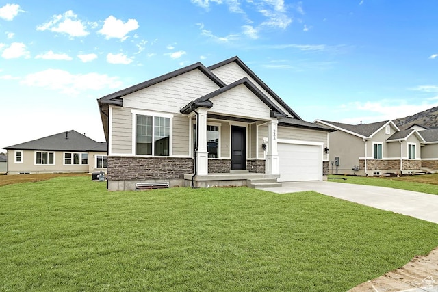 233 E 580 N, Providence, UT 84332 - view of front of home with stone siding, concrete driveway, a front lawn, and a garage
