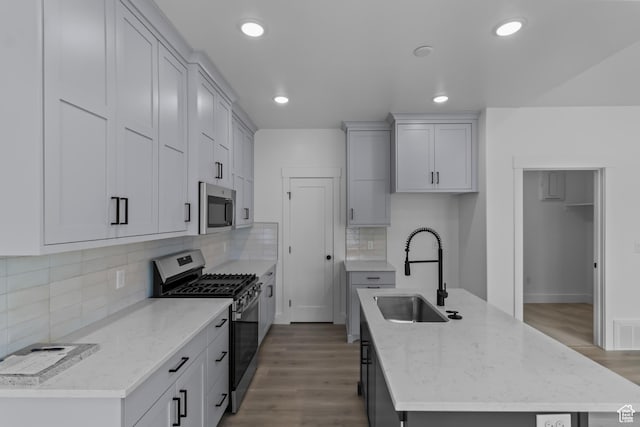 233 E 580 N, Providence, UT 84332 - kitchen with appliances with stainless steel finishes, a kitchen island with sink, wood finished floors, light stone counters, and recessed lighting