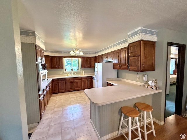 1177 W 2060 N, Helper, UT 84526 - kitchen featuring white appliances, a peninsula, a chandelier, light countertops, and a textured ceiling