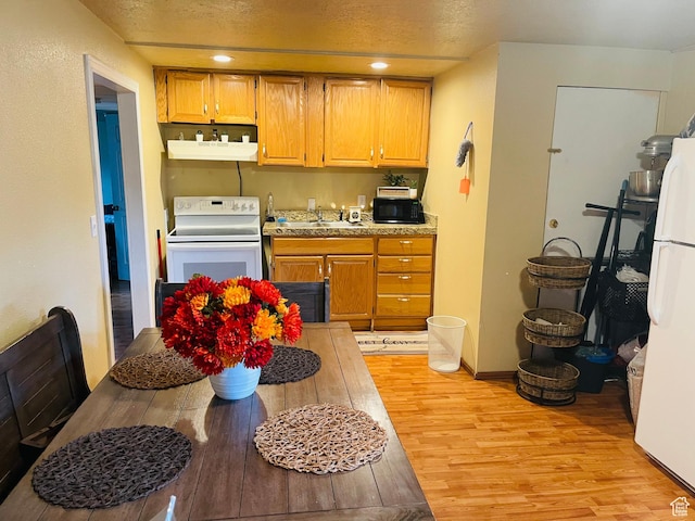 1086 W Wenco Dr S, Salt Lake City, UT 84104 - kitchen with white appliances, light wood-style floors, range hood, light countertops, and a textured ceiling