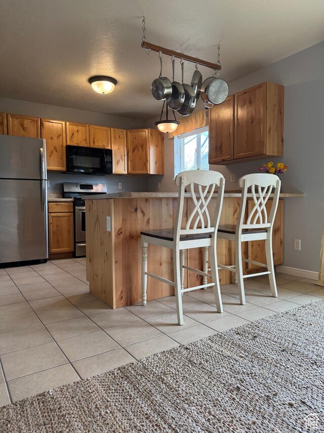 471 N 100 W, Kamas, UT 84036 - kitchen with appliances with stainless steel finishes, a peninsula, light tile patterned floors, and a kitchen breakfast bar