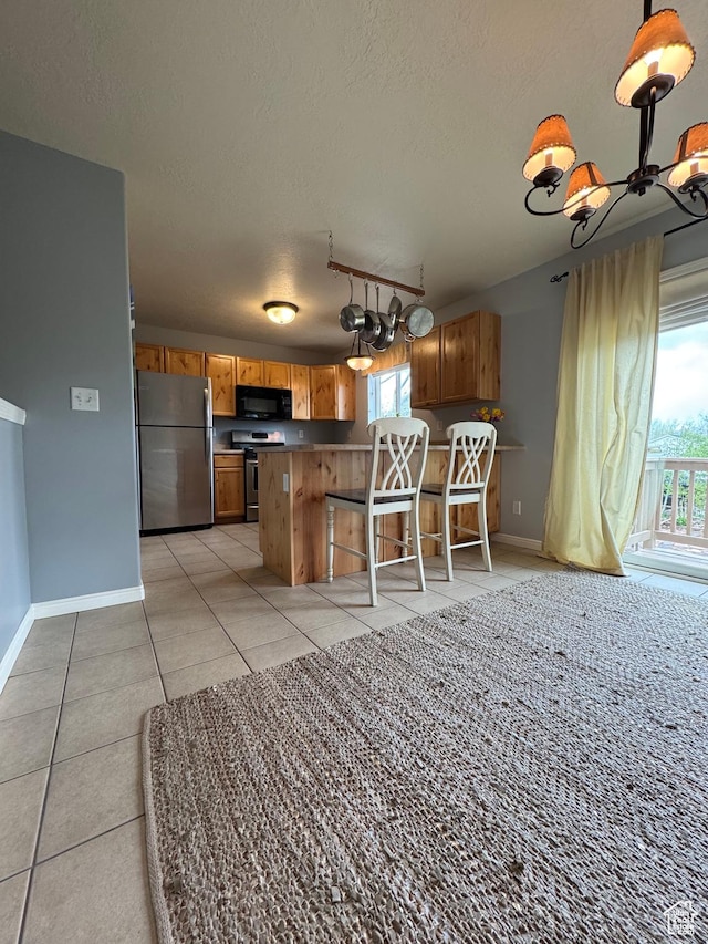 471 N 100 W, Kamas, UT 84036 - kitchen with appliances with stainless steel finishes, a chandelier, a textured ceiling, brown cabinetry, and light tile patterned flooring