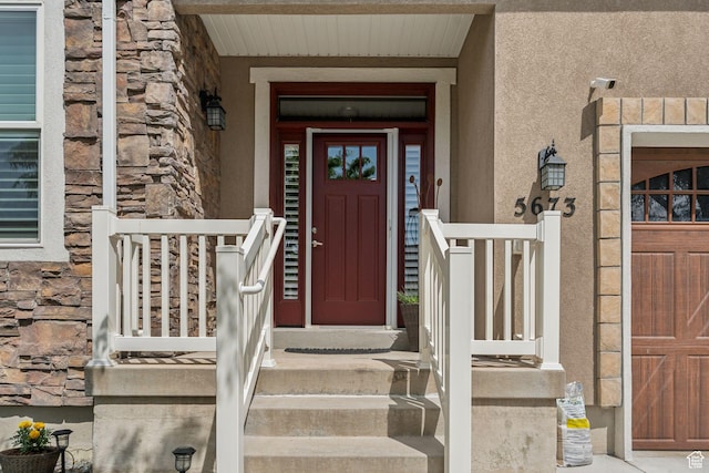 5673 S Wilson View Ct, Holladay, UT 84121 - doorway to property with stucco siding, stone siding, a garage, and a porch