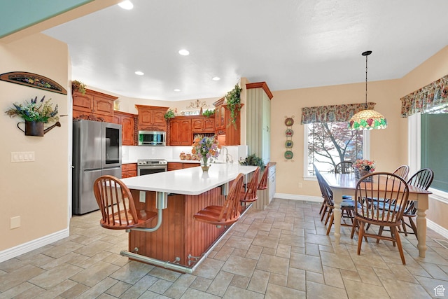 97 Hillsborough Dr, Pleasant View, UT 84414 - kitchen with stainless steel appliances, brown cabinets, a peninsula, stone tile floors, and light countertops