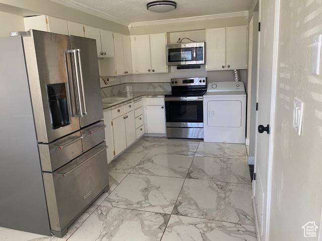 314 W Center St N Unit 135, Bountiful, UT 84010 - kitchen with appliances with stainless steel finishes, washer / clothes dryer, ornamental molding, white cabinetry, and light marble finish floors