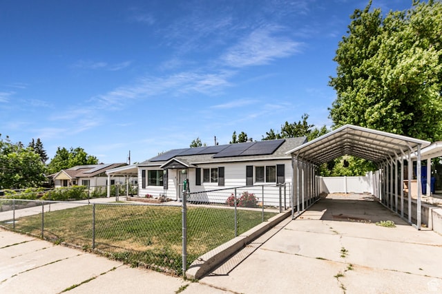 317 Highland Dr, Tooele, UT 84074 - view of front of home with a fenced front yard, a detached carport, driveway, and roof mounted solar panels