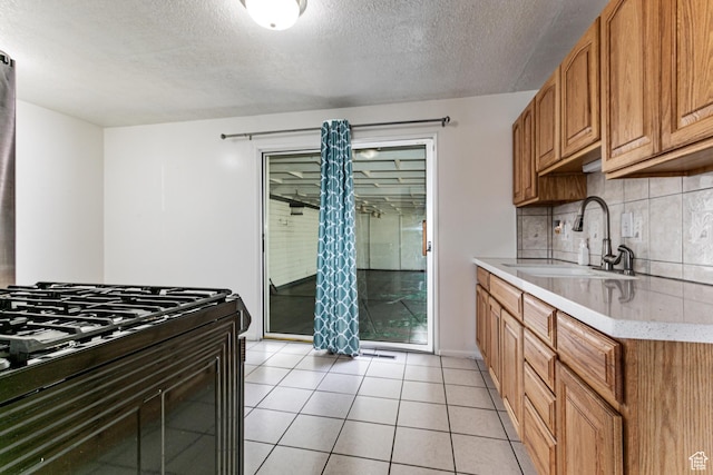 317 Highland Dr, Tooele, UT 84074 - kitchen featuring backsplash, a textured ceiling, black gas range, light tile patterned floors, and brown cabinets