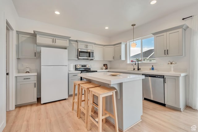 7256 N Green Pasture Ln, Eagle Mountain, UT 84005 - kitchen with stainless steel appliances, gray cabinets, a kitchen bar, light countertops, and light wood-type flooring